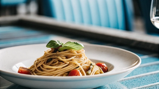 Fresh spaghetti with anchovies and cherry tomatoes served on white plate in Italian restaurant