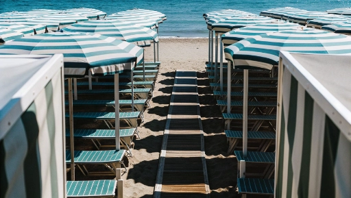 Rows of colorful beach umbrellas and sunbeds on Terracina sandy beach with blue sea
