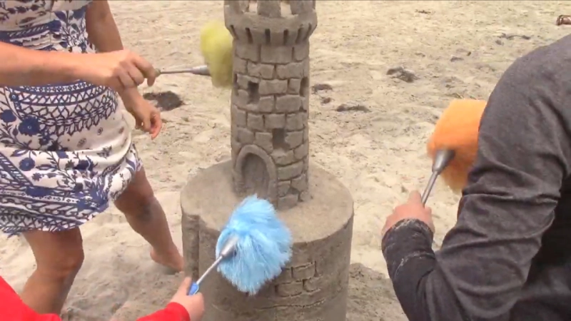 Family with children building sandcastles on Terracina beach with colorful umbrellas